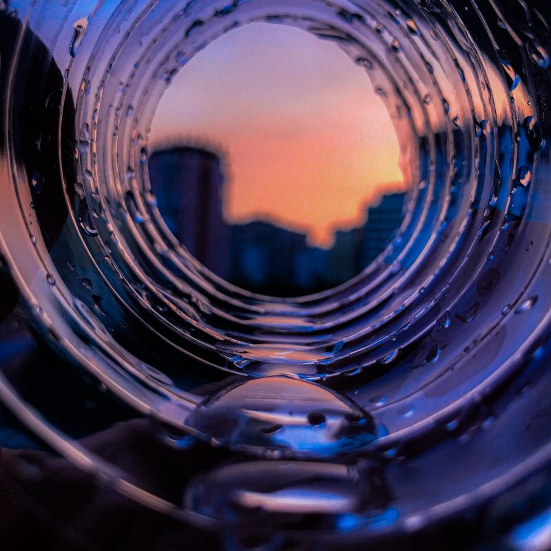 vue à travers un tube transparent montrant un coucher de soleil rose et orange