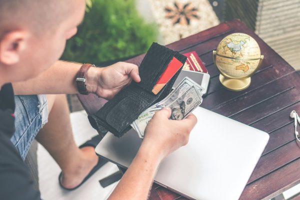 personne consultant son portefeuille vide avec facture et globe terrestre sur le bureau