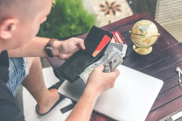 personne consultant son portefeuille vide avec facture et globe terrestre sur le bureau