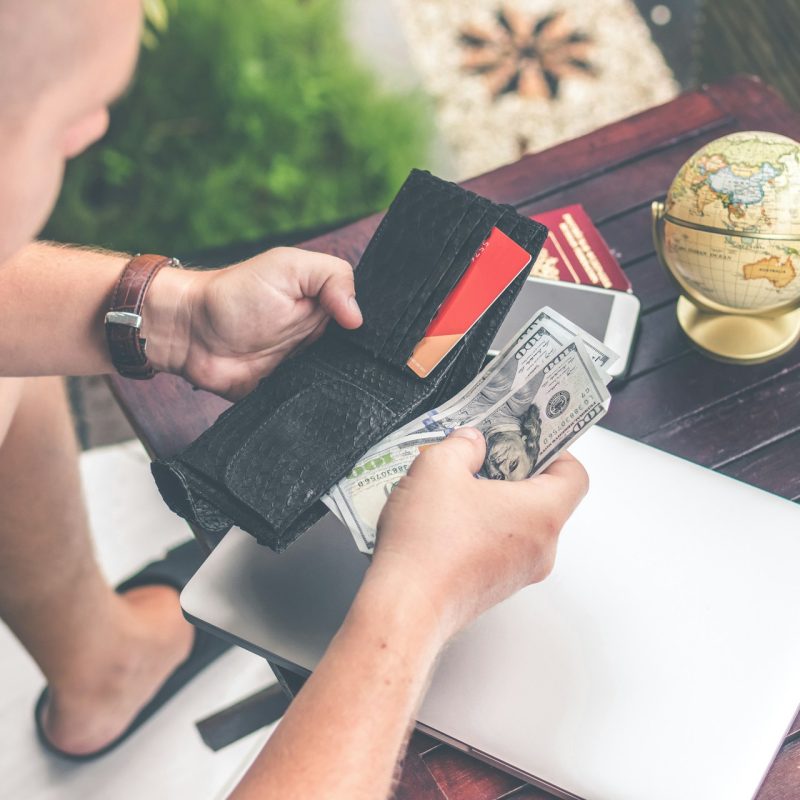 personne consultant son portefeuille vide avec facture et globe terrestre sur le bureau