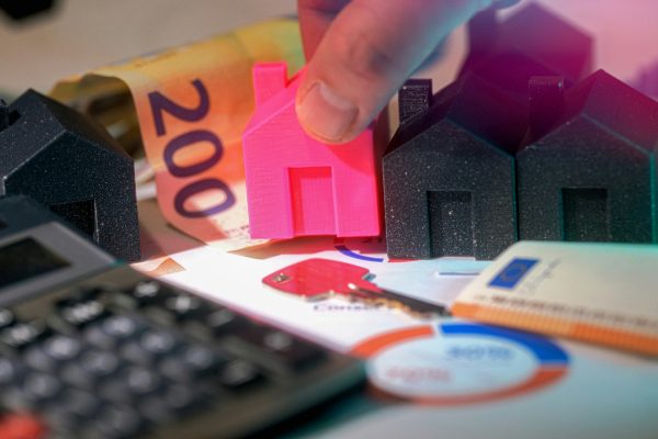 maisons miniatures roses et noires avec billets et calculatrice pour investissement locatif