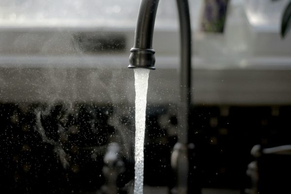 robinet ouvert avec jet d'eau visible, symbolisant la consommation d'eau