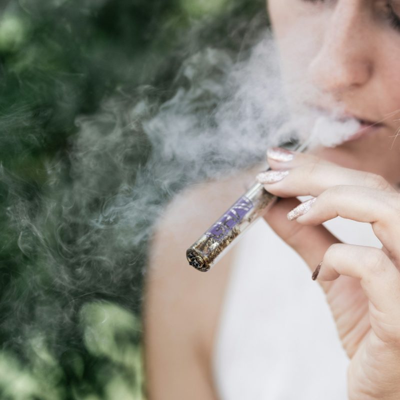 femme fumant une cigarette électronique avec vapeur visible