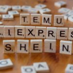 Wooden Scrabble tiles display popular e-commerce platforms on a wooden surface.