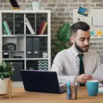 a man sitting at a desk in front of a laptop