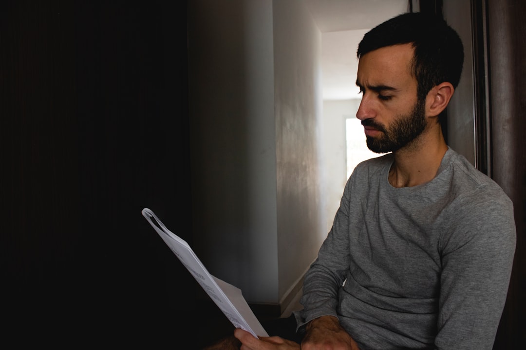 man in gray crew neck shirt holding white printer paper