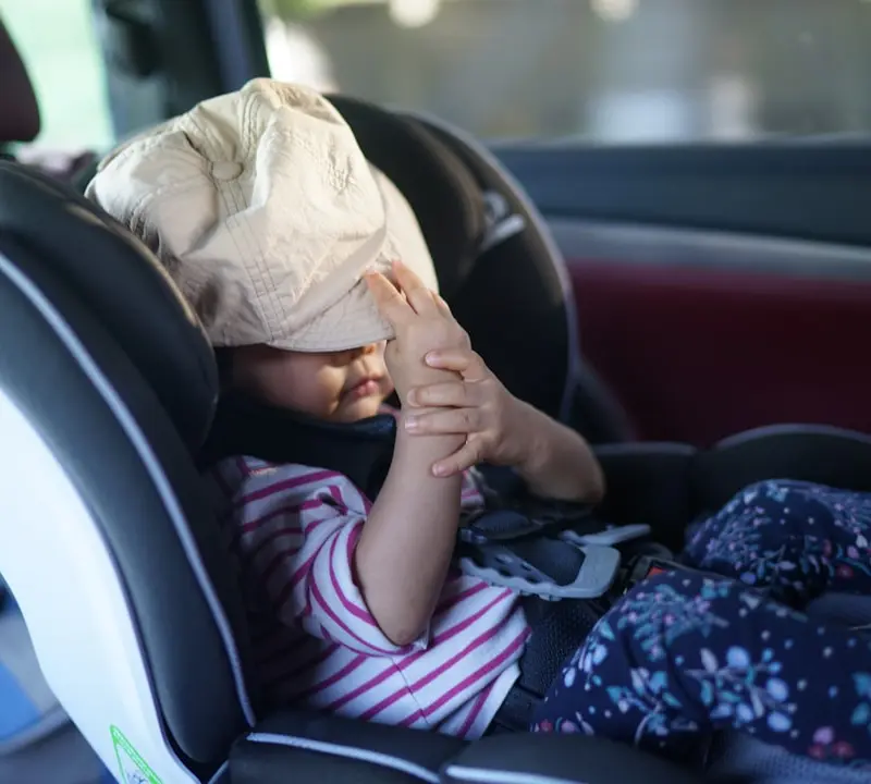 A child has a bag over their head in car.