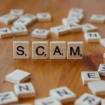 Scam spelled with scrabbles on a wooden table
